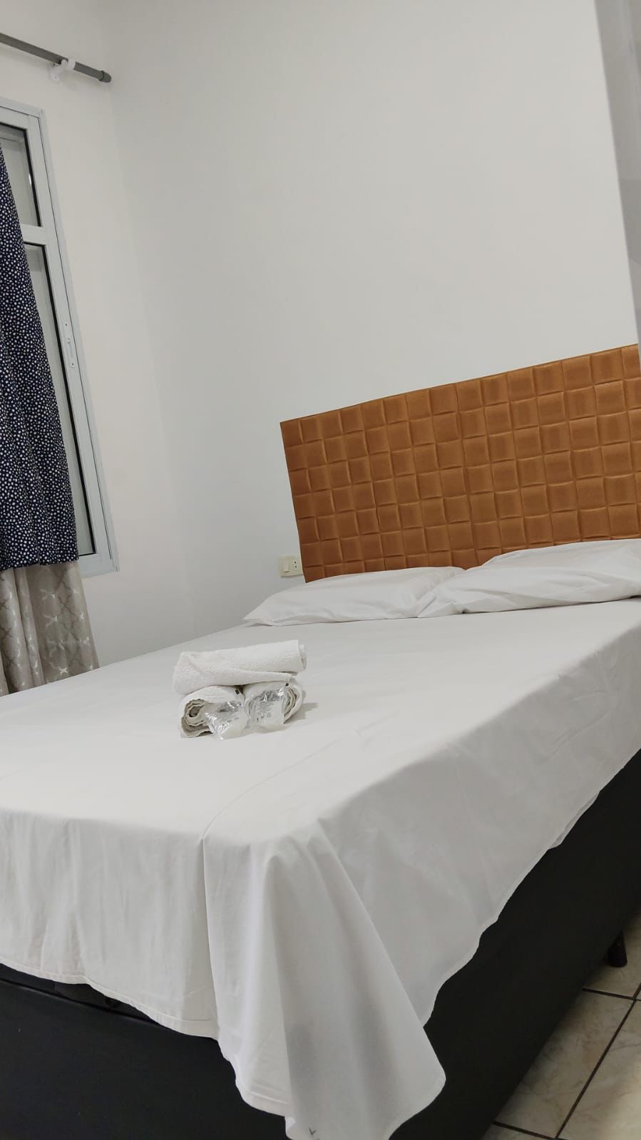 Quarto com cama, janela e cortinas em ambiente confortável